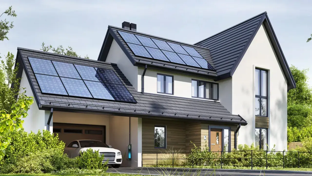 Nowoczesny dom z panelami fotowoltaicznymi na dachu. Obok stoi biały samochód z ładowarką. To właśnie oze co to – energia odnawialna w praktyce.