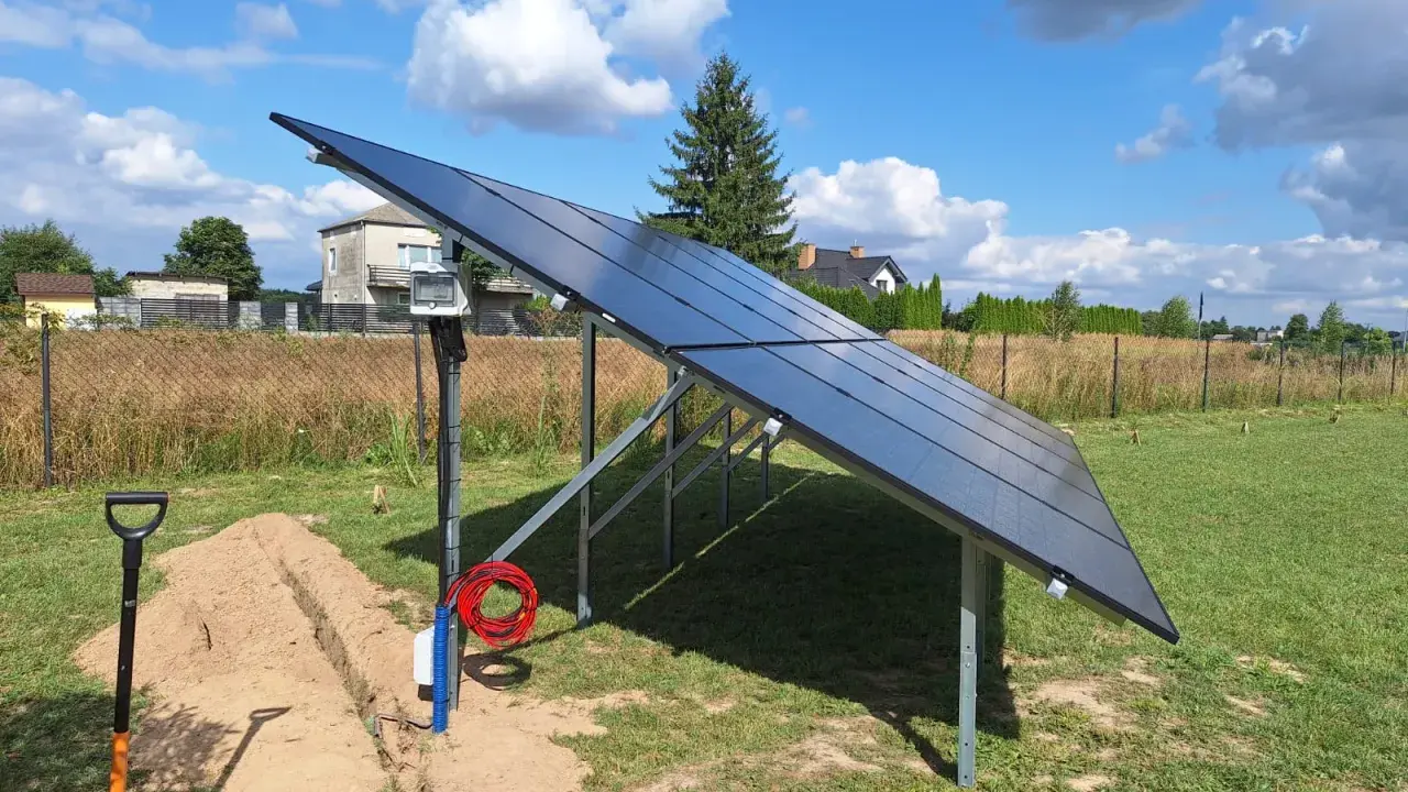 Instalacja paneli fotowoltaicznych na gruncie. Widać okablowanie i wykop, co sugeruje, jaka odległość falownika od paneli jest planowana.