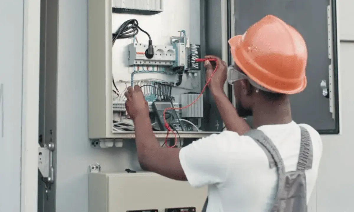 Elektryk w kasku sprawdza instalację fotowoltaiczną. Dowiedz się, jak obniżyć napięcie w sieci fotowoltaika.