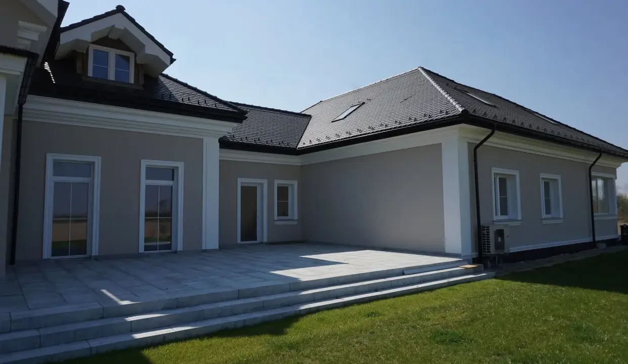 Elegancki dom z tarasem i schodami. Widoczny ozdobny gzyms co to za element architektoniczny, dodający klasy.
