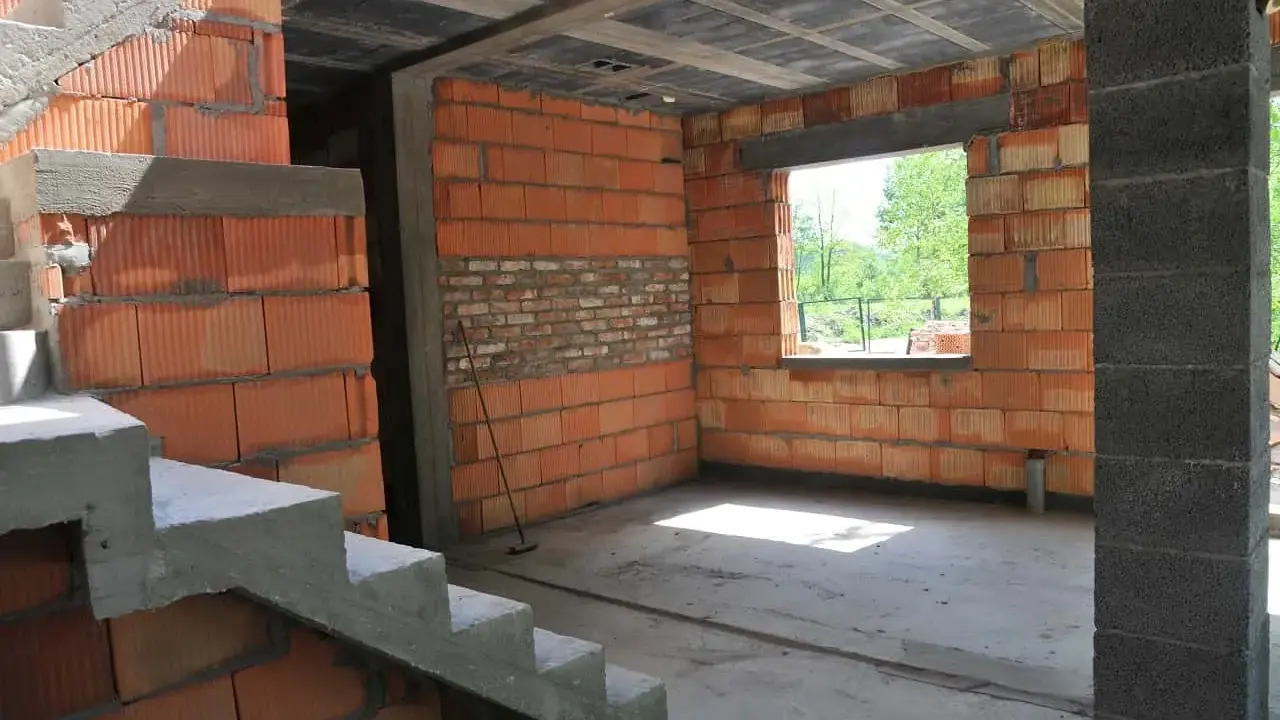 Trwa przekształcenie budynku gospodarczego na mieszkalny. Widoczne schody, ściany z pustaków ceramicznych i betonowy strop.