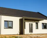 Nowy, biały dom z ciemnym dachem i drzwiami. Wokół plac budowy, ale czy nadzór budowlany przyjeżdża na odbiór domu?