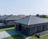 Nowoczesne domy z szarym dachem kopertowym. Konstrukcja dachu jest estetyczna i funkcjonalna, idealnie komponuje się z ceglaną elewacją.