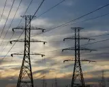 Dwa wysokie słupy energetyczne na tle zachodzącego słońca. Zastanawiasz się, ile za kilowat prądu?