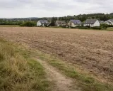 Pola uprawne obok domów, idealne miejsce do zastanowienia się, jak odrolnić działkę i stworzyć własne ogrody.