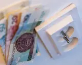 Polskie banknoty obok gniazdka elektrycznego, symbolizujące koszty energii. PGE okres rozliczeniowy G11.