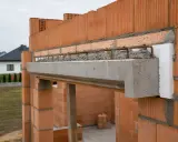 Solidna belka nad oknem, wykonana z betonu i zbrojenia, stanowi kluczowy element konstrukcyjny.