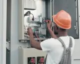 Elektryk w kasku sprawdza instalację fotowoltaiczną. Dowiedz się, jak obniżyć napięcie w sieci fotowoltaika.