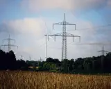 Pole pszenicy, wiatraki i wysokie słupy energetyczne tworzą krajobraz nowoczesnej sieci OSD.