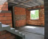 Trwa przekształcenie budynku gospodarczego na mieszkalny. Widoczne schody, ściany z pustaków ceramicznych i betonowy strop.