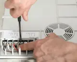 Ręczne podłączanie przewodów do urządzenia. Jaki przekrój kabla do mocy 10 kW? Widać zaciski oznaczone jako L1, L2, N.