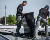 Pracownicy montują panele fotowoltaiczne, przygotowując potwierdzenie przyłączenia mikroinstalacji do sieci.