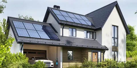 Nowoczesny dom z panelami fotowoltaicznymi na dachu. Obok stoi biały samochód z ładowarką. To właśnie oze co to – energia odnawialna w praktyce.