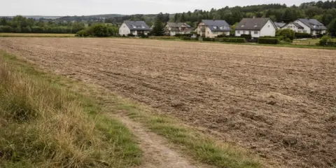 Pola uprawne obok domów, idealne miejsce do zastanowienia się, jak odrolnić działkę i stworzyć własne ogrody.