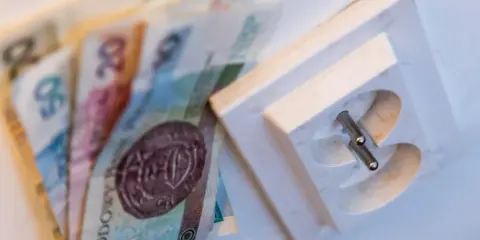Polskie banknoty obok gniazdka elektrycznego, symbolizujące koszty energii. PGE okres rozliczeniowy G11.