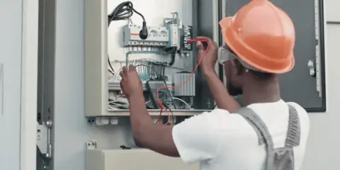 Elektryk w kasku sprawdza instalację fotowoltaiczną. Dowiedz się, jak obniżyć napięcie w sieci fotowoltaika.