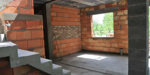 Trwa przekształcenie budynku gospodarczego na mieszkalny. Widoczne schody, ściany z pustaków ceramicznych i betonowy strop.