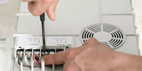 Ręczne podłączanie przewodów do urządzenia. Jaki przekrój kabla do mocy 10 kW? Widać zaciski oznaczone jako L1, L2, N.