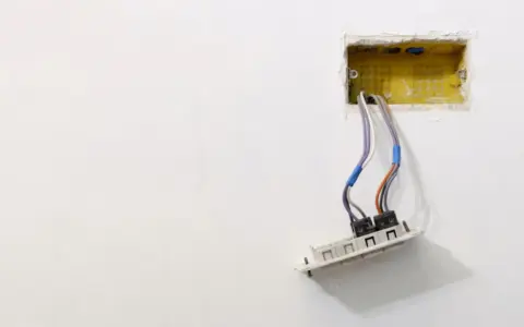 Instalacja elektryczna: przewody wychodzące z żółtej puszki, gotowe do montażu gniazdka. Dowiedz się, jak osadzić puszki elektryczne.