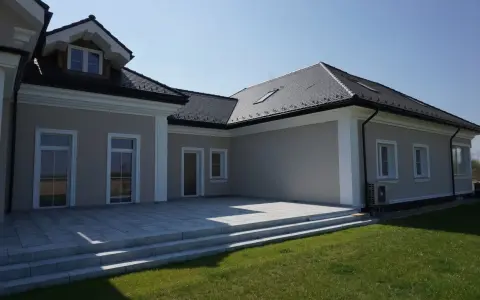 Elegancki dom z tarasem i schodami. Widoczny ozdobny gzyms co to za element architektoniczny, dodający klasy.