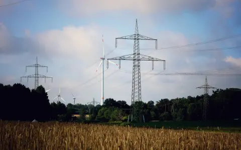 Pole pszenicy, wiatraki i wysokie słupy energetyczne tworzą krajobraz nowoczesnej sieci OSD.