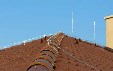 System piorunochronu na brązowym dachu z dachówki ceramicznej, chroniący przed uderzeniami pioruna.