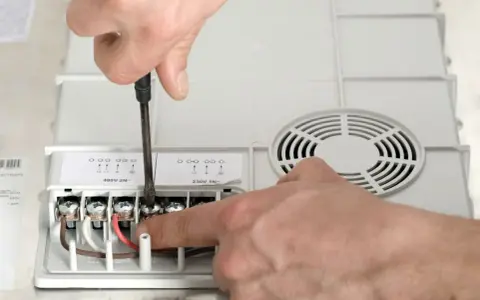 Ręczne podłączanie przewodów do urządzenia. Jaki przekrój kabla do mocy 10 kW? Widać zaciski oznaczone jako L1, L2, N.