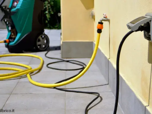 Jak zamontować gniazdko na elewacji? Wąż ogrodowy podłączony do kranu i kabel zasilający do gniazdka na ścianie.