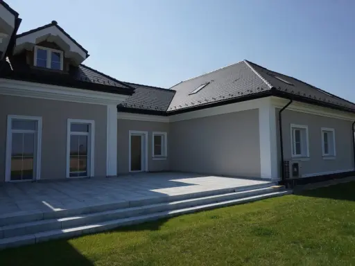 Elegancki dom z tarasem i schodami. Widoczny ozdobny gzyms co to za element architektoniczny, dodający klasy.