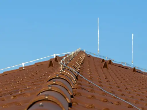 System piorunochronu na brązowym dachu z dachówki ceramicznej, chroniący przed uderzeniami pioruna.