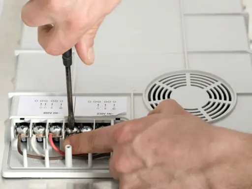 Ręczne podłączanie przewodów do urządzenia. Jaki przekrój kabla do mocy 10 kW? Widać zaciski oznaczone jako L1, L2, N.