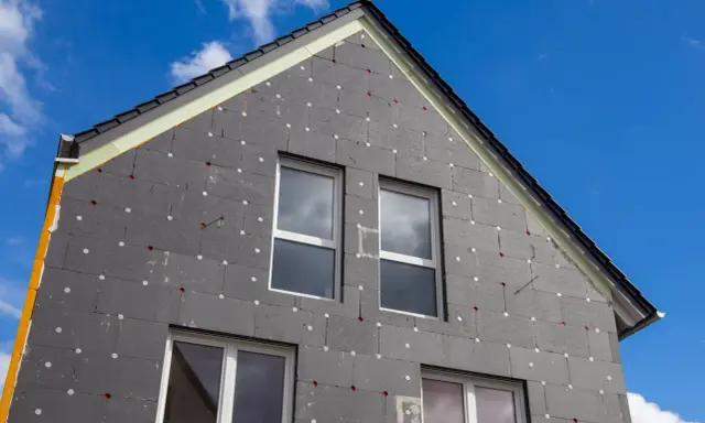 Izolacja domu z grafitowego styropianu, z widocznymi oknami i dachem. Czy styropian się pali? To pytanie nurtuje wielu, ale nowoczesne materiały są bezpieczne.