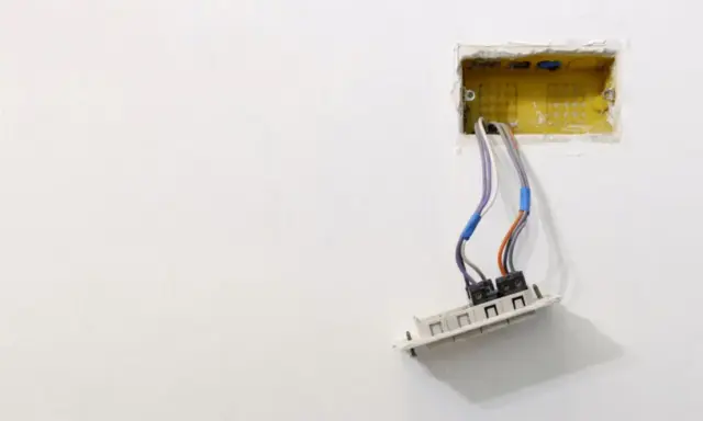 Instalacja elektryczna: przewody wychodzące z żółtej puszki, gotowe do montażu gniazdka. Dowiedz się, jak osadzić puszki elektryczne.