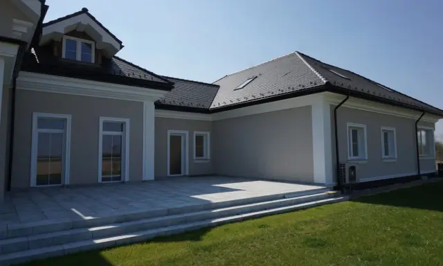 Elegancki dom z tarasem i schodami. Widoczny ozdobny gzyms co to za element architektoniczny, dodający klasy.