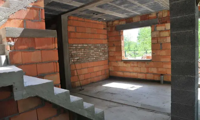 Trwa przekształcenie budynku gospodarczego na mieszkalny. Widoczne schody, ściany z pustaków ceramicznych i betonowy strop.