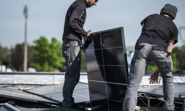 Pracownicy montują panele fotowoltaiczne, przygotowując potwierdzenie przyłączenia mikroinstalacji do sieci.