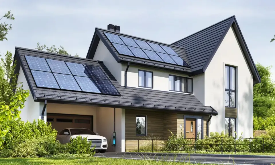 Nowoczesny dom z panelami fotowoltaicznymi na dachu. Obok stoi biały samochód z ładowarką. To właśnie oze co to – energia odnawialna w praktyce.