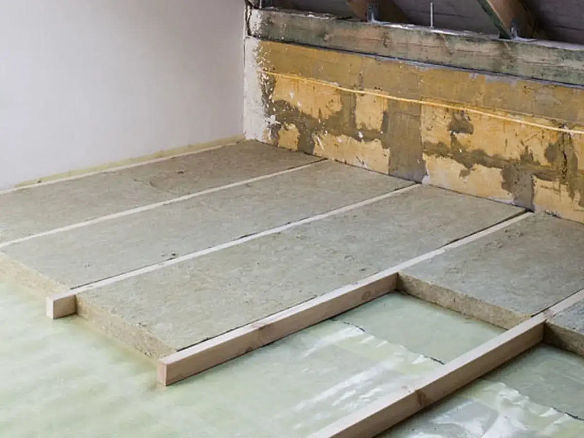 Układanie wełny mineralnej na stropie betonowym. To kluczowy etap prac, kt&oacute;ry zapewni izolację termiczną i akustyczną.