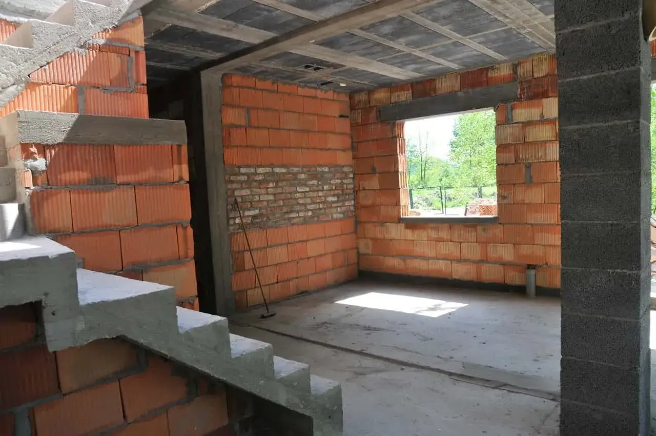 Trwa przekształcenie budynku gospodarczego na mieszkalny. Widoczne schody, ściany z pustaków ceramicznych i betonowy strop.