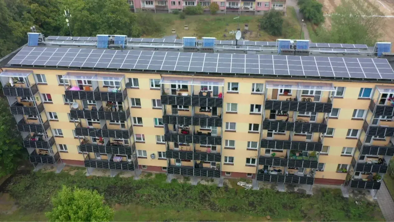 Blok mieszkalny z panelami słonecznymi na dachu i balkonach. Mieszkańcy tego budynku to prosument lokatorski, czerpiący energię ze słońca.