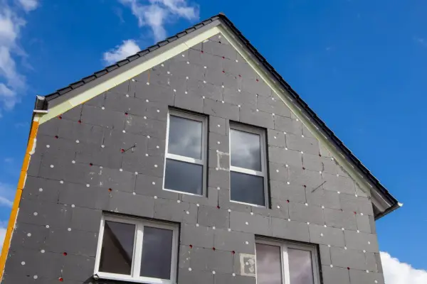 Izolacja domu z grafitowego styropianu, z widocznymi oknami i dachem. Czy styropian się pali? To pytanie nurtuje wielu, ale nowoczesne materiały są bezpieczne.