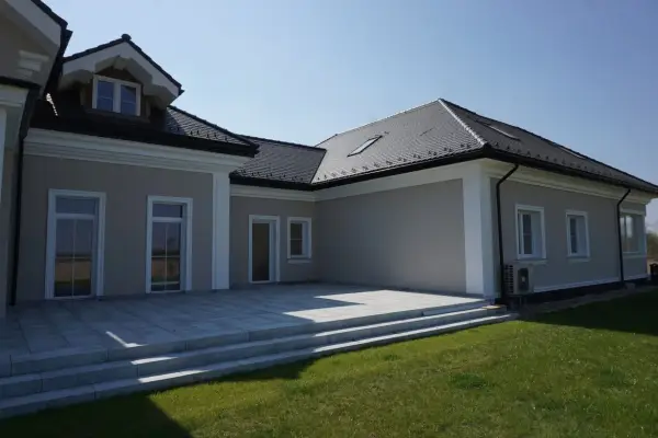 Elegancki dom z tarasem i schodami. Widoczny ozdobny gzyms co to za element architektoniczny, dodający klasy.